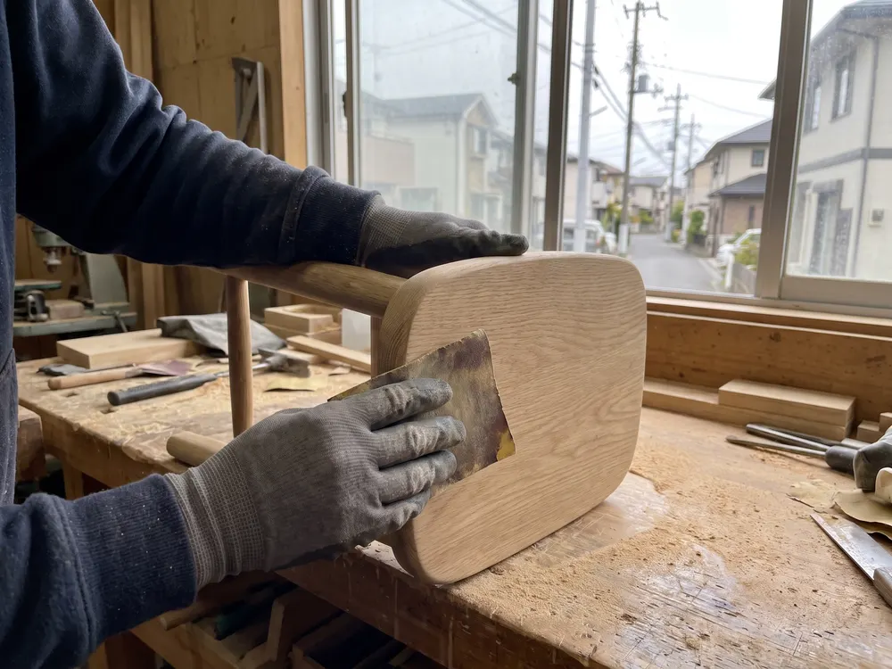 椅子の座る所の角を、紙やすりで磨く手元