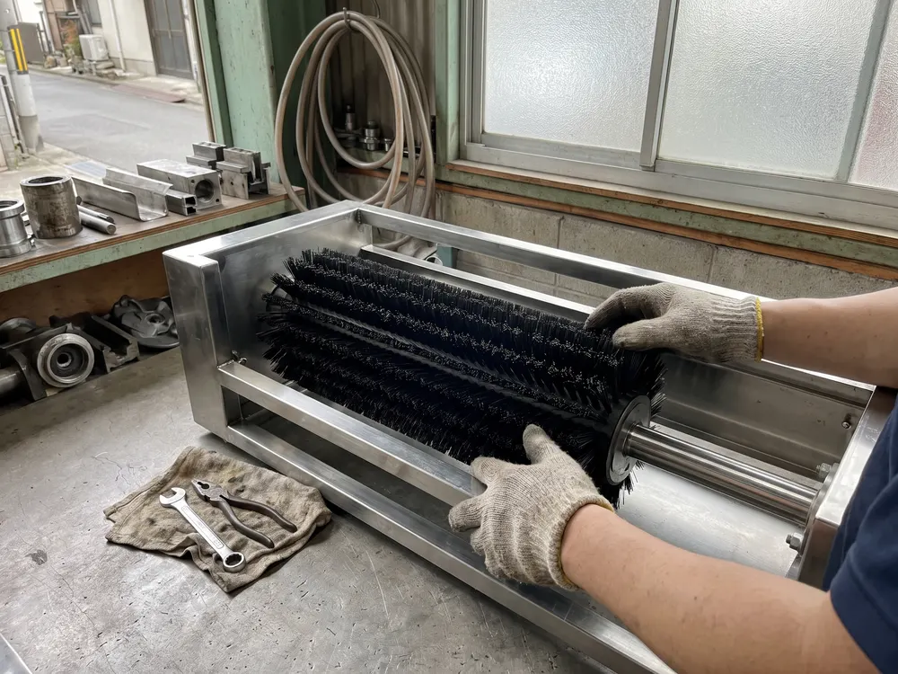 機械の枠に、筒の形のブラシを取り付ける手元